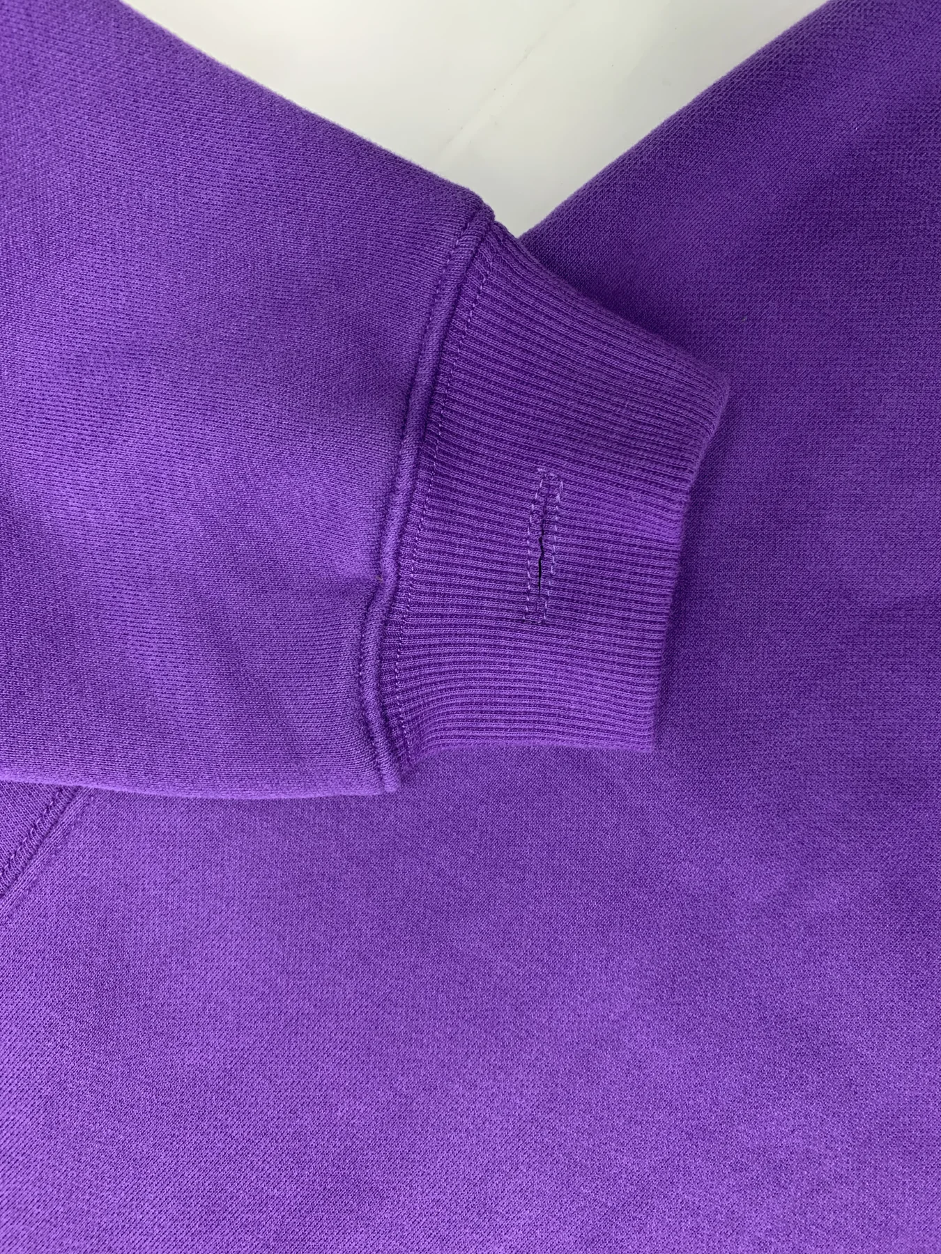Cuff opening and rib seam detail on a purple sample, showing a specific construction point to record during approval.